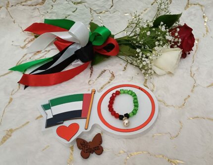 Handgemaakte armband van zwarte, groene en rode kralen met witte parels.