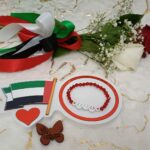 Handgemaakte armband van rode kralen en simile-gezichten van VAE-vlagkleuren.