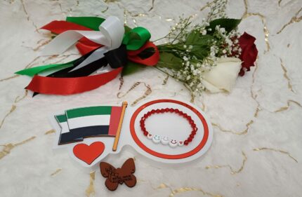 Handgemaakte armband van rode kralen en simile-gezichten van VAE-vlagkleuren.