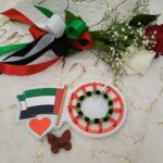 Handgemaakte armband van zwarte en groene kralen met rode hartvormige kralen en een wit lint.